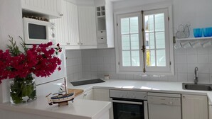 Cocina moderna con muebles blancos, lavavajillas Bosch, microondas y ventana con vidrio esmerilado.