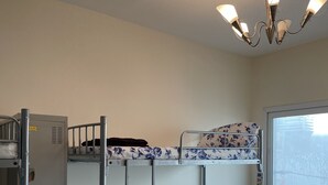 A bunk bed room with a window, a ceiling light, and a radiator.