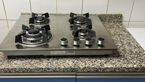 A kitchen with a gas stove, granite countertop, and blue cabinets.