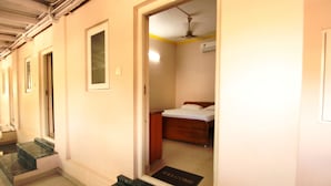 A hotel corridor with a marble staircase, a door with a 'Welcome' mat, and a room with a bed and a bedside table. - Sibi Lodge (Coimbatore)
