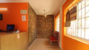A reception area with a wooden counter, a computer, and a wall mural. - Sibi Lodge (Coimbatore)