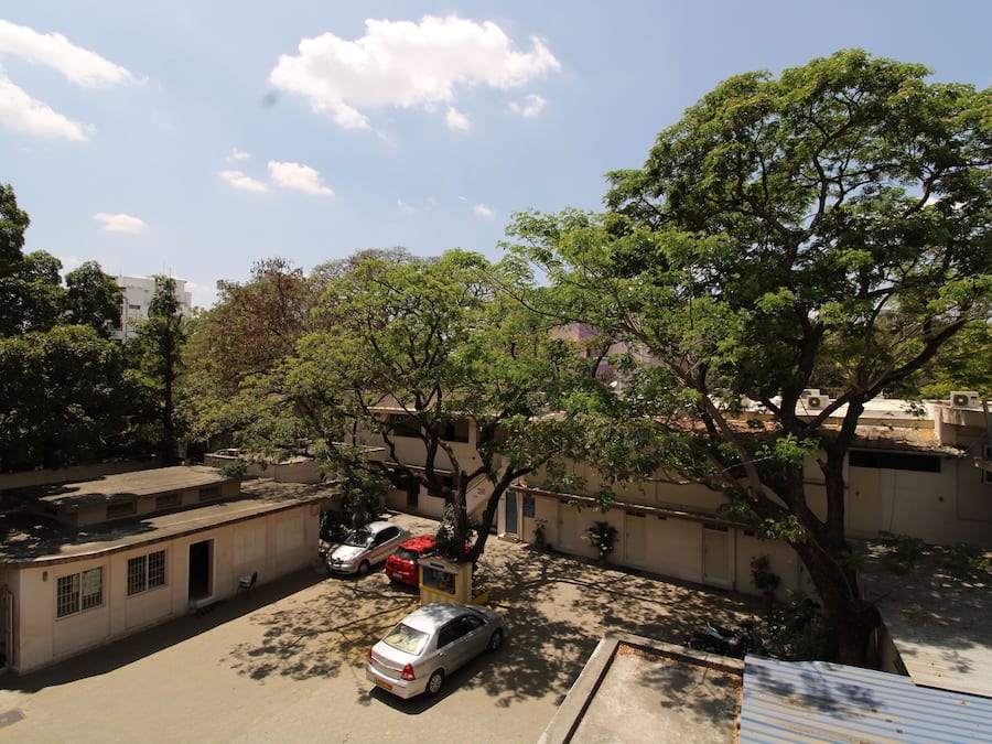 A parking area with cars, a building, and trees.