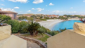 Blick auf die Küste mit Strand, blauem Himmel und Gebäuden im Hintergrund.