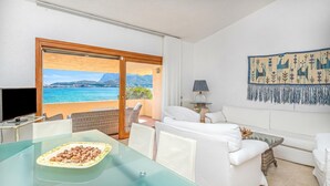 Ein Zimmer mit Glastisch, weißem Sofa und Meerblick.