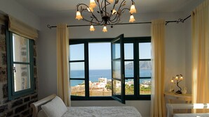 A bedroom with a bed, a desk, and a view of the sea. - Luxury Villa with Mountain and Sea View (Siteia)
