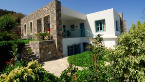 A two-story house with stone walls, a balcony, and a garden. - Luxury Villa with Mountain and Sea View (Siteia)