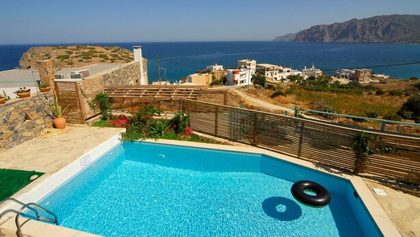 A swimming pool with a view of the sea and buildings in the background. - Luxury Villa with Mountain and Sea View (Siteia)