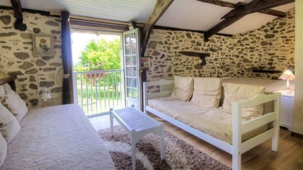 A rustic room with a stone wall, a bed, a sofa, and a small table. - bed & Breakfast (Sonnac)