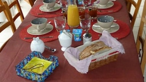 A breakfast table set with cups, bowls, a coffee pot, and a bottle of orange juice. - bed & Breakfast (Sonnac)