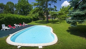 A swimming pool with a surrounding grassy area and red lounge chairs. - bed & Breakfast (Sonnac)