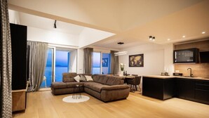 Una sala moderna con un sofá seccional, un comedor y una cocina.