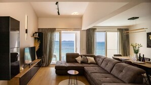 Una sala de estar moderna con un sofá seccional grande, un televisor de pantalla plana y un comedor con mesa y sillas.