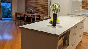 Eine moderne Küche mit Kochinsel, Holztisch und Blick ins Freie.