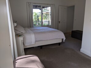 A bedroom with a bed, a bench, a door, and a window. - Foxhouse (Aireys Inlet)