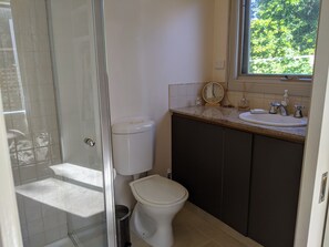 A bathroom with a toilet, sink, and a window. - Foxhouse (Aireys Inlet)