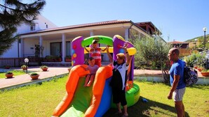 Un tobogán inflable en un área verde, con un edificio al fondo.