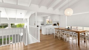 A spacious kitchen with a central island, wooden dining table, and white cabinetry. - Peppertree Jervis Bay - Pet Friendly Beachfront with Sea Views (Callala Beach)