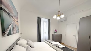 Una habitación de hotel moderna con una cama grande, un armario, un escritorio y un cuadro en la pared.