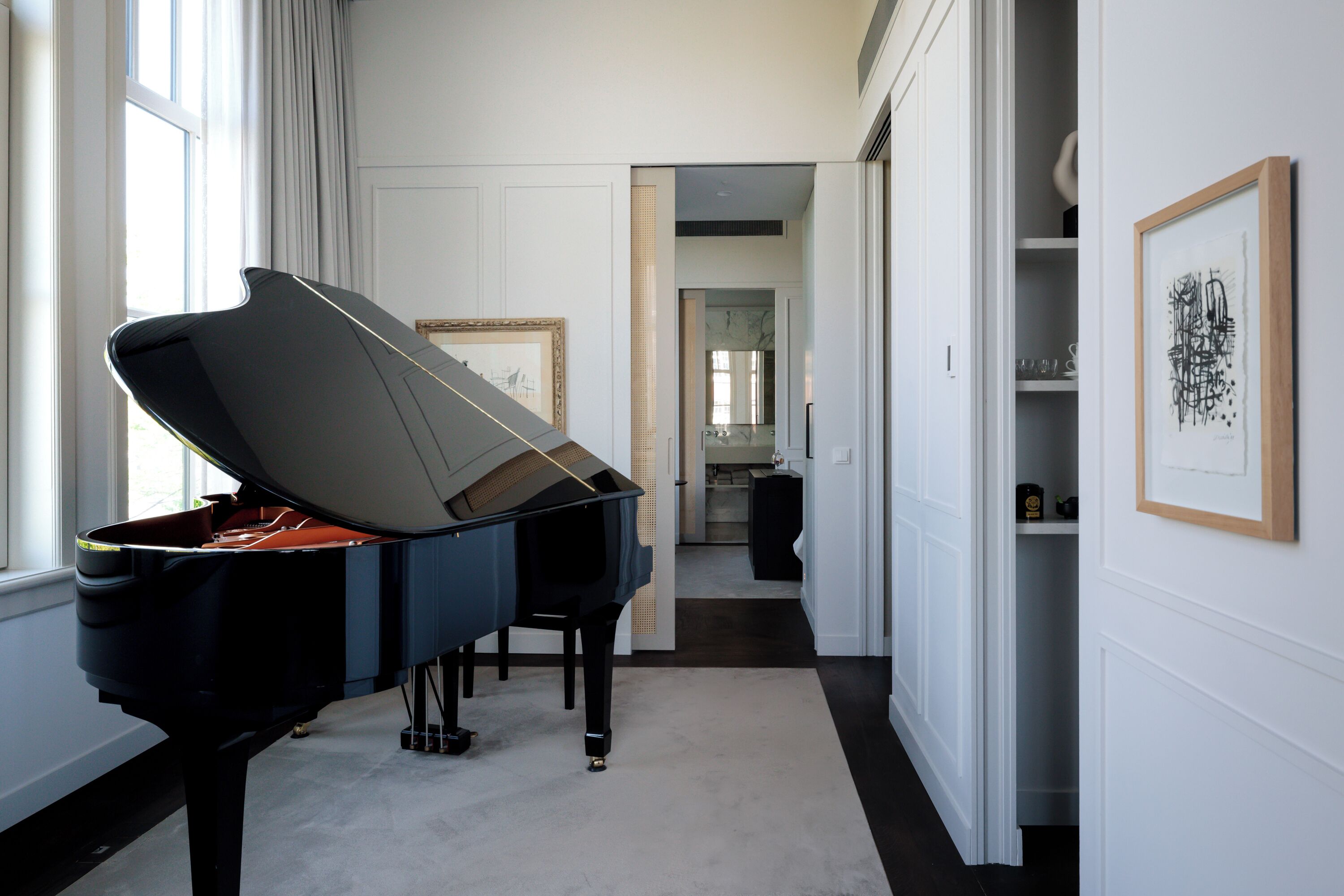 A grand piano in a spacious, well-lit hallway with a view to a dining area.
