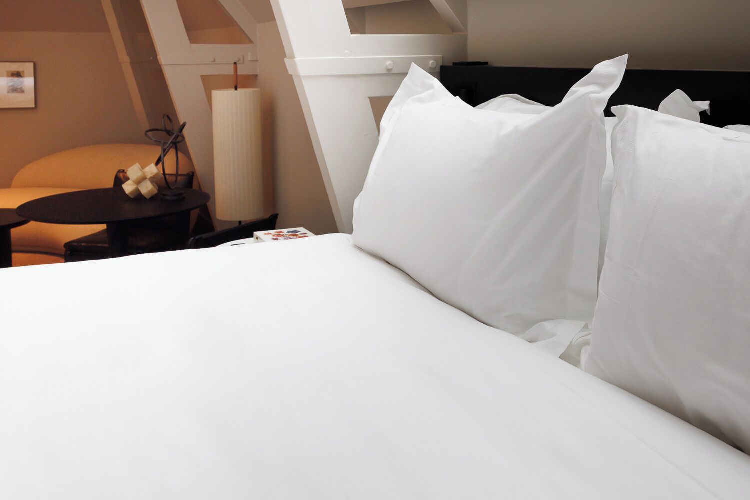 A neatly made bed with white linens in a hotel room.