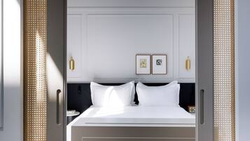 A hotel room with a bed, two framed pictures on the wall, and a bedside table with a radio.