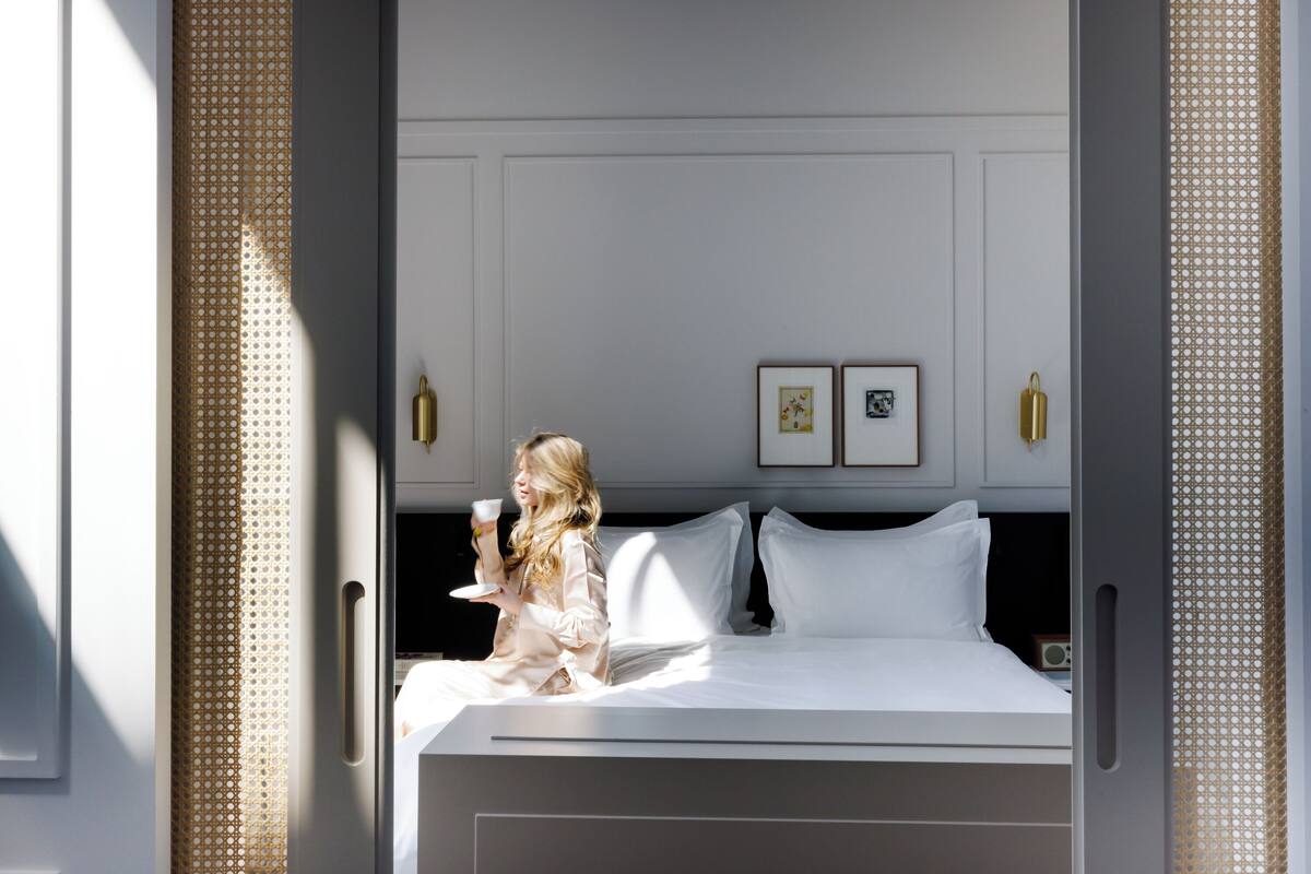 A modern hotel room with a large bed, a bedside table, and a nightstand.