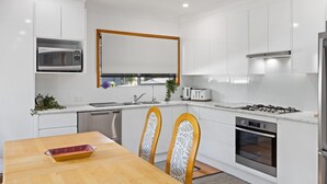 A modern kitchen with white cabinetry, a built-in microwave, a gas stove, and a dishwasher.
