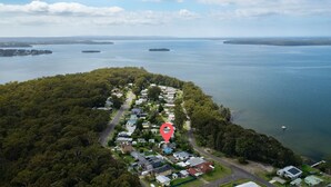 An aerial view of a coastal residential area with houses, roads, and a large body of water.