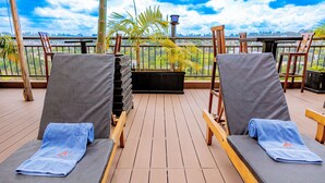Een terras met twee loungestoelen, elk voorzien van een handdoek, en een bijzettafeltje.