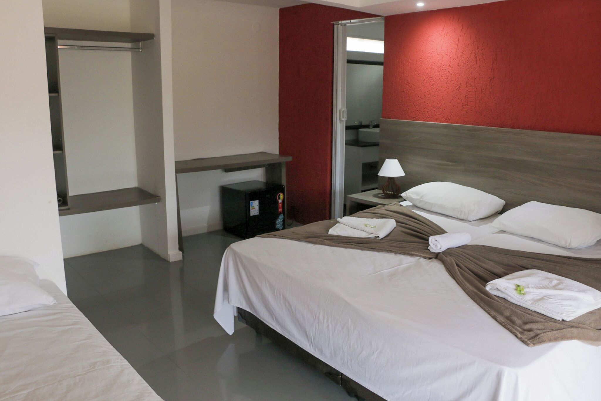 A hotel room with a bed, a bedside table, a lamp, and a mirror.
