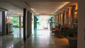Un vestíbulo de hotel con mostrador de recepción, zona de estar y vistas al exterior.