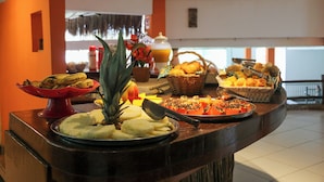 Un bufé con diversos platos, incluyendo frutas, pan y pastelería.