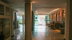Un vestíbulo espacioso con techo alto, grandes columnas y vistas al exterior.