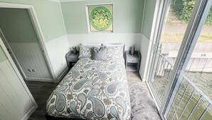 Een slaapkamer met een bed, twee nachtkastjes, een raam en een deur.