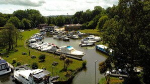Een jachthaven met aangemeerde boten, een klein gebouw en een gazon met picknicktafels.