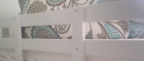 A bunk bed with patterned bedding in a room with a window.