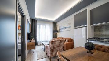 A modern living room with a sofa, a dining table, and a kitchen area with a refrigerator.