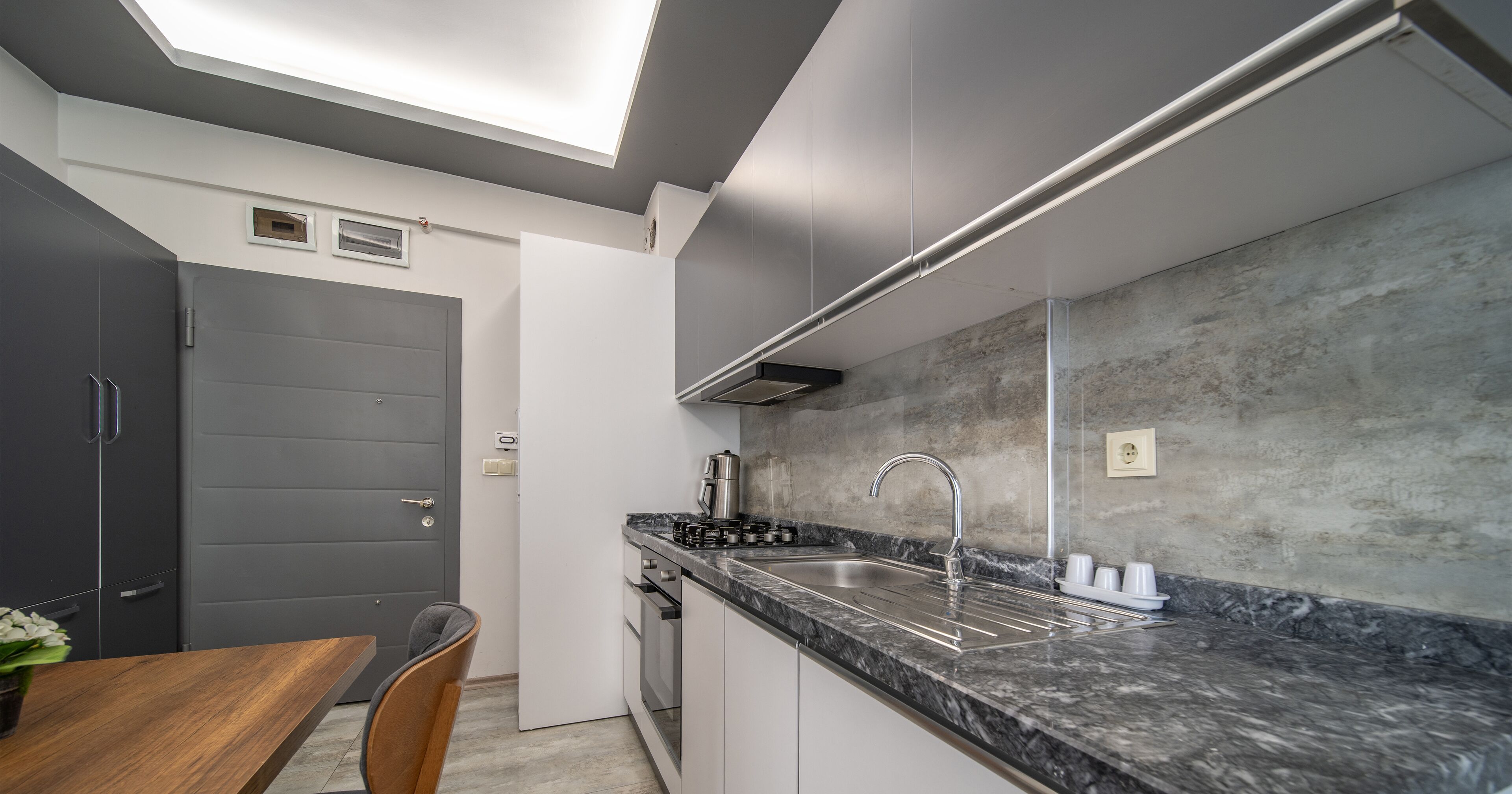A modern kitchen with a marble countertop, stainless steel sink, and a built-in oven.