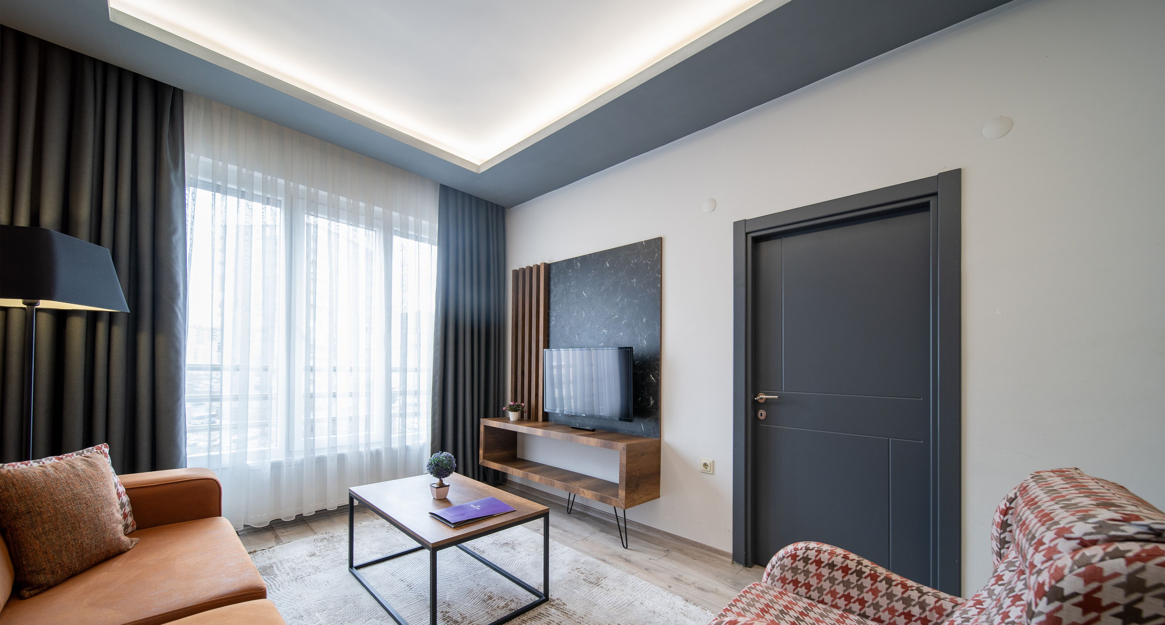A modern living room with a sofa, a coffee table, a TV, and a door.