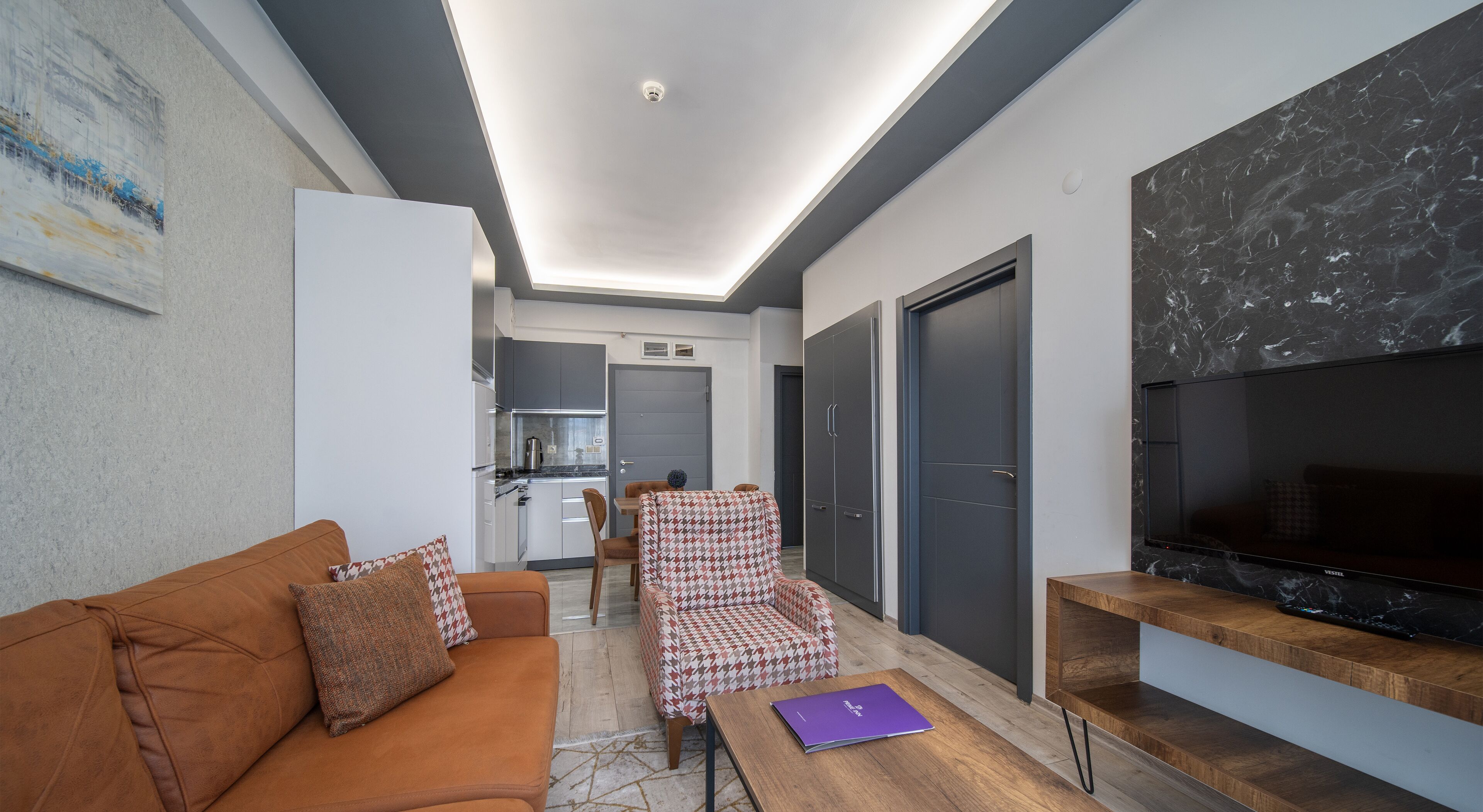 Ein modernes Wohnzimmer mit Sofa, Sessel und TV-Möbel.