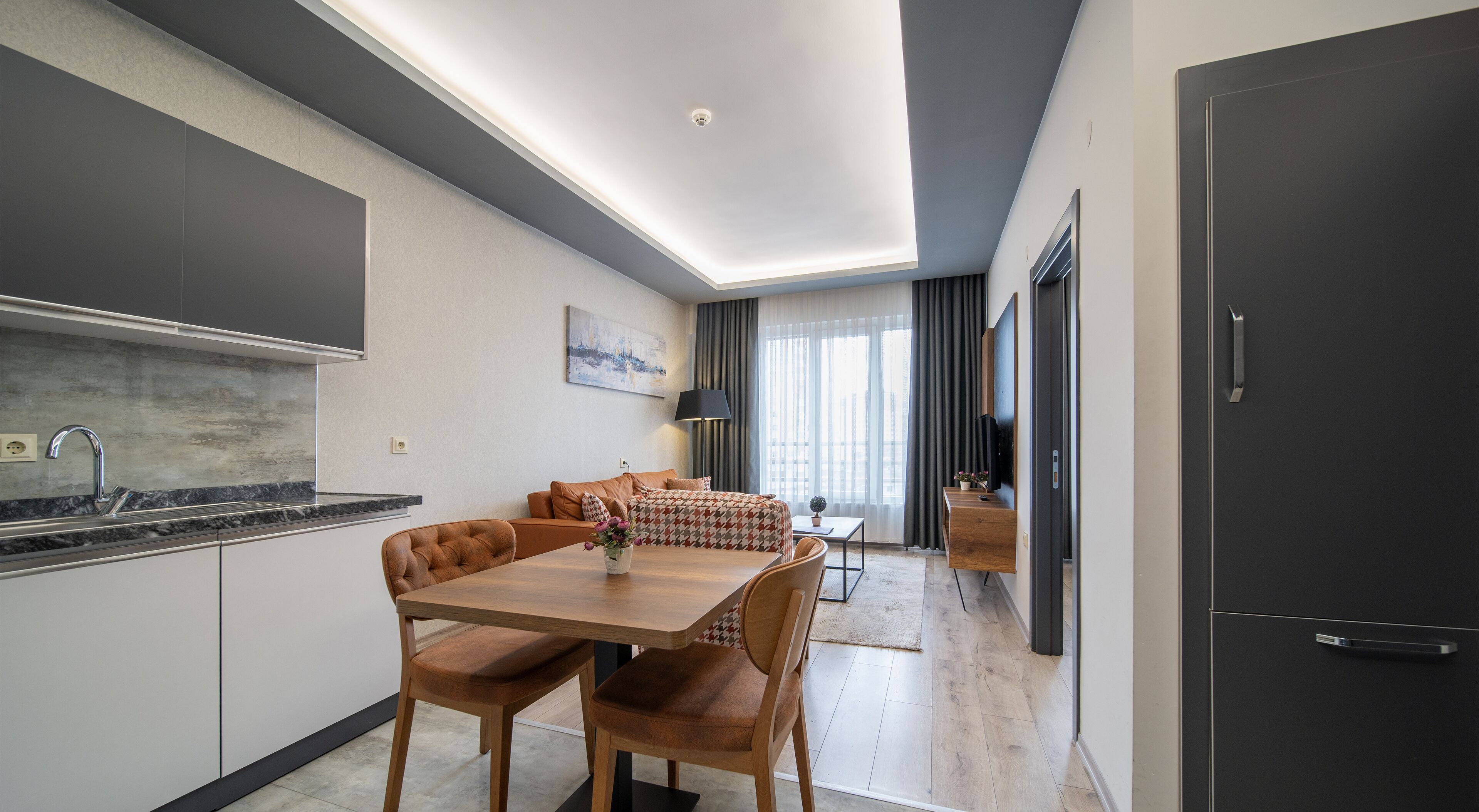 Eine moderne Küche mit Marmorarbeitsplatte und einem eingebauten Ofen. Es gibt einen Essbereich mit einem Holztisch und Stühlen.