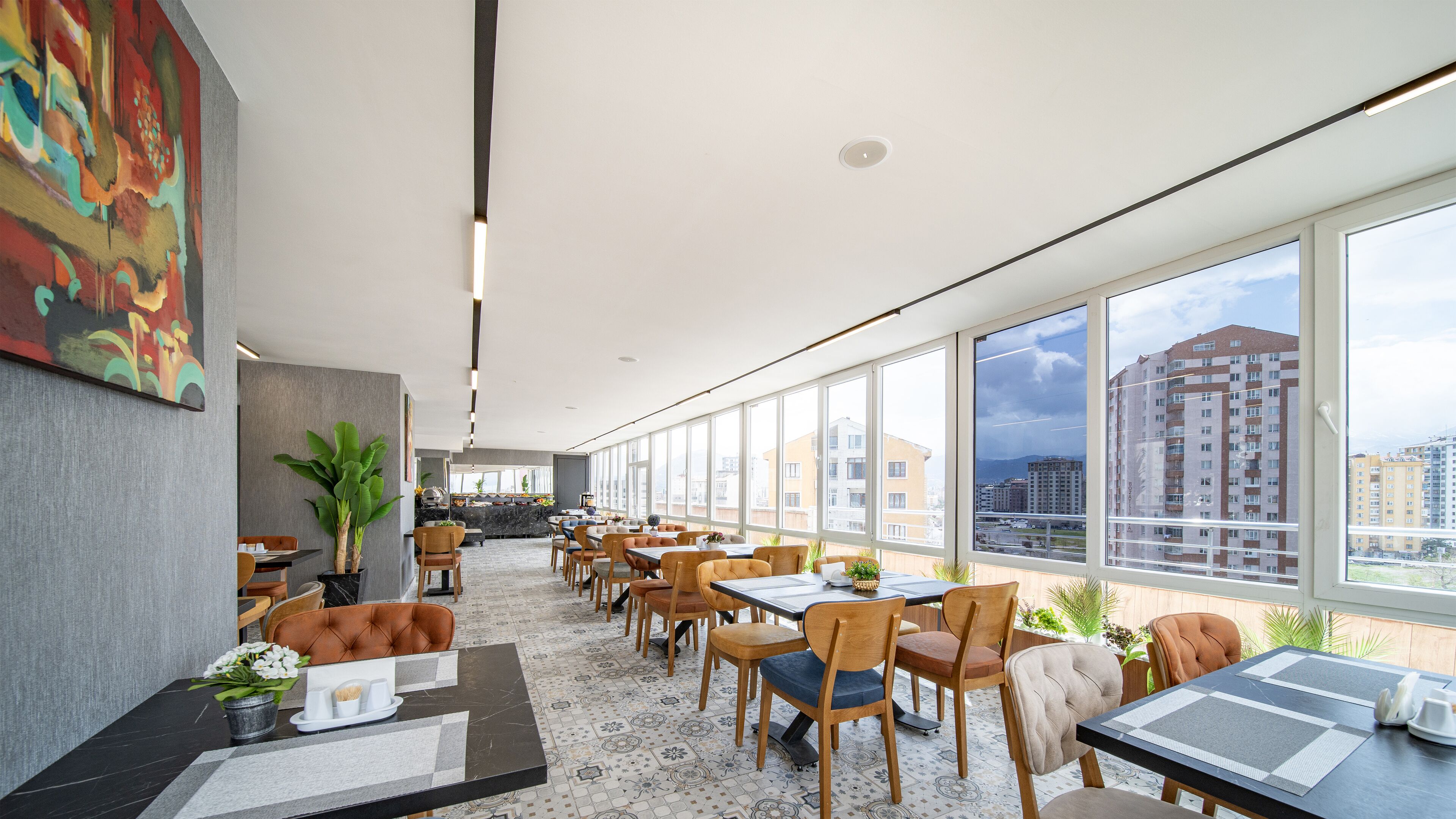 A modern dining area with large windows, a view of the city, and a mix of wooden and upholstered chairs.