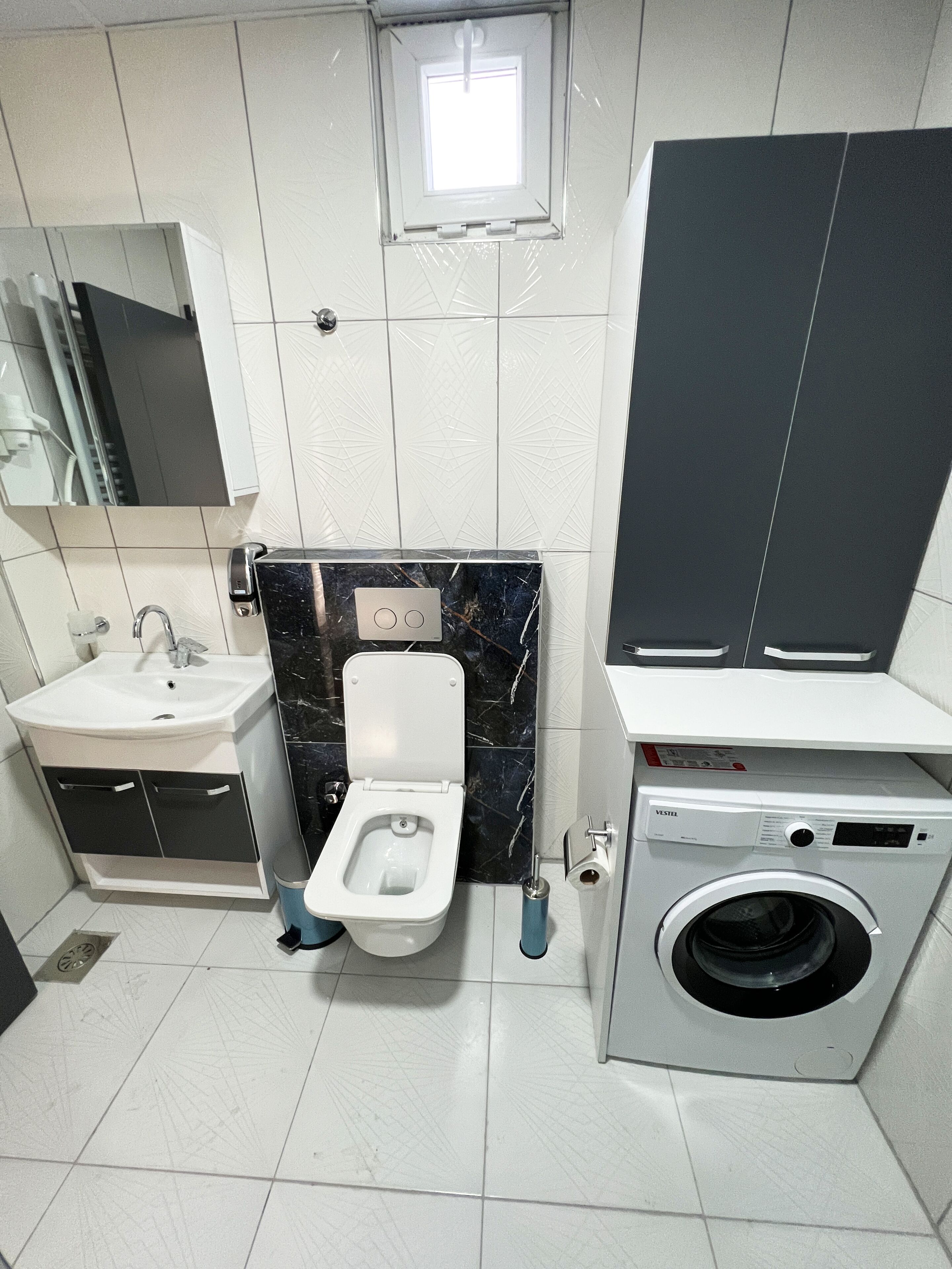 A modern bathroom with a toilet, sink, and washing machine.