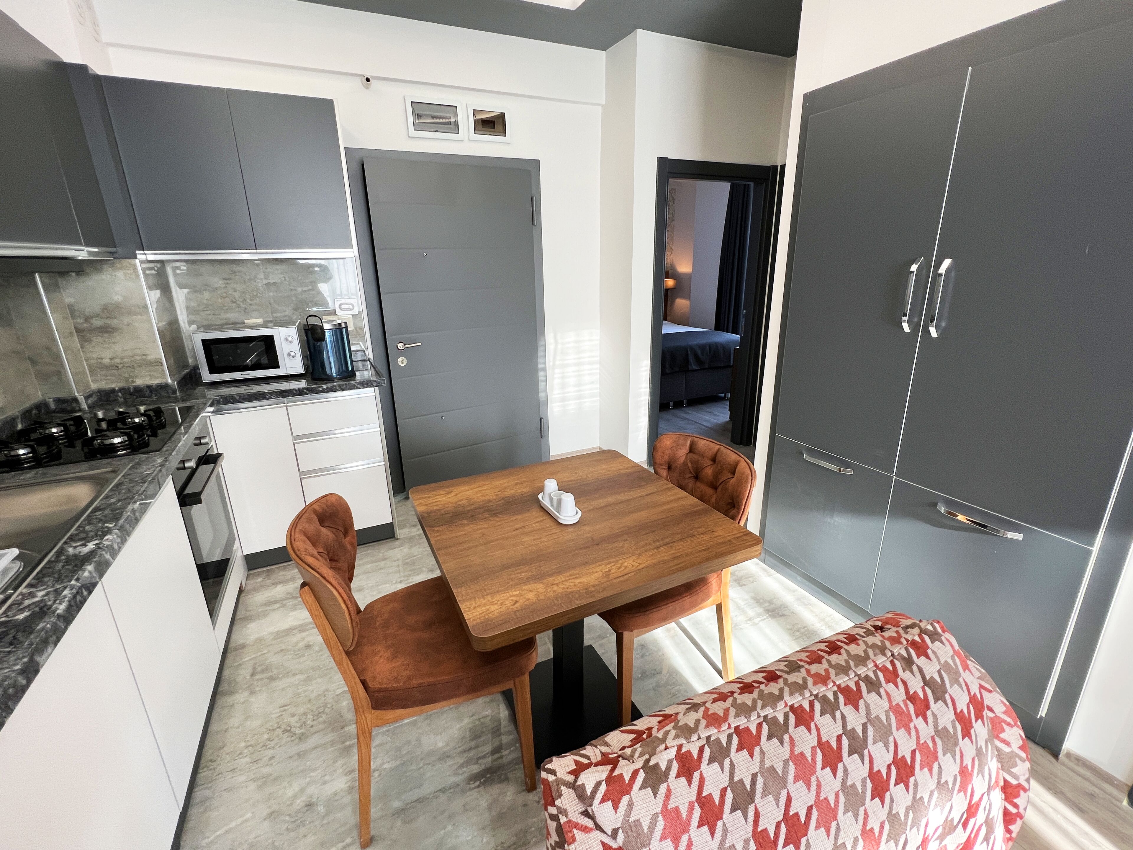 A compact kitchen with a dining area, a microwave, a stove, and a bench.