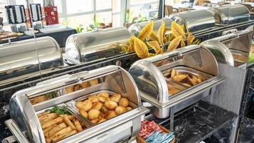 A buffet with various food items including fried items and bread.