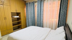 Ein Schlafzimmer mit Bett, Kleiderschrank und Vorhängen.