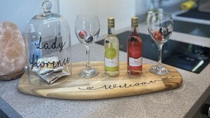 Een houten dienblad met een welkomstbericht op een aanrecht, met een fles witte wijn, een fles rosé en twee wijnglazen met decoratieve accessoires.