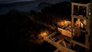 A coastal view with a pier extending into the sea, a building with a balcony overlooking the ocean, and a clear sky with a crescent moon. - 3 bedroom, 3 bath beautiful oceanfront condo on the quiet shore of Cherry Grove. (North Myrtle Beach)