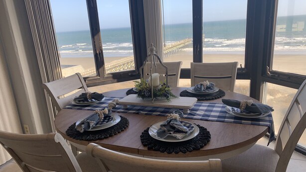 A dining table set for four with a view of the beach. - 3 bedroom, 3 bath beautiful oceanfront condo on the quiet shore of Cherry Grove. (North Myrtle Beach)