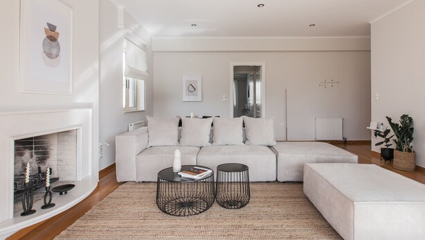A modern living room with a sectional sofa, two black wire coffee tables, a fireplace, and a large mirror on the wall. - Exquisite 2BR Apartment (Agia Paraskevi)